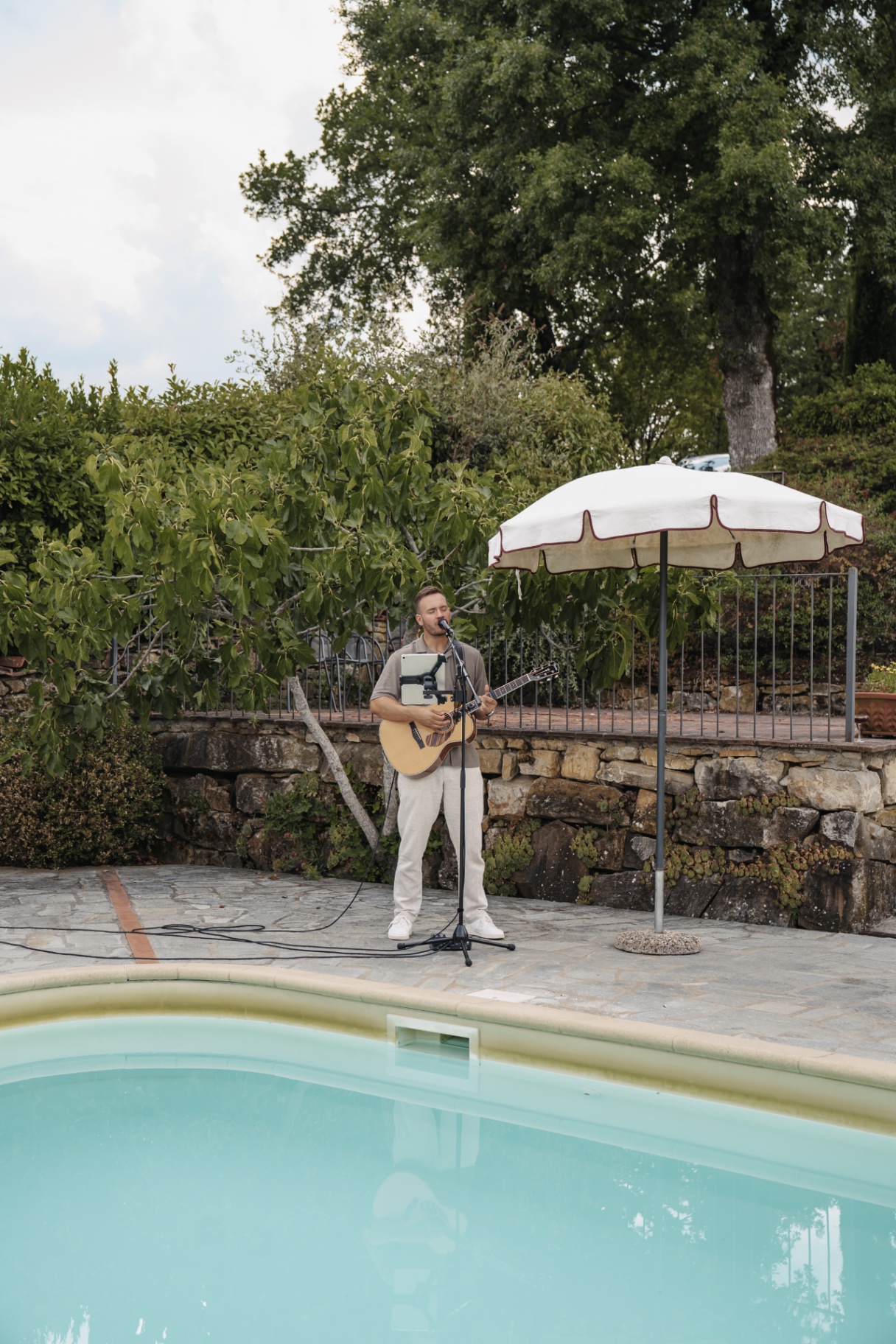 Dennis Ross singt mit Akustikgitarre am Pool einer Hochzeit in der Toskana