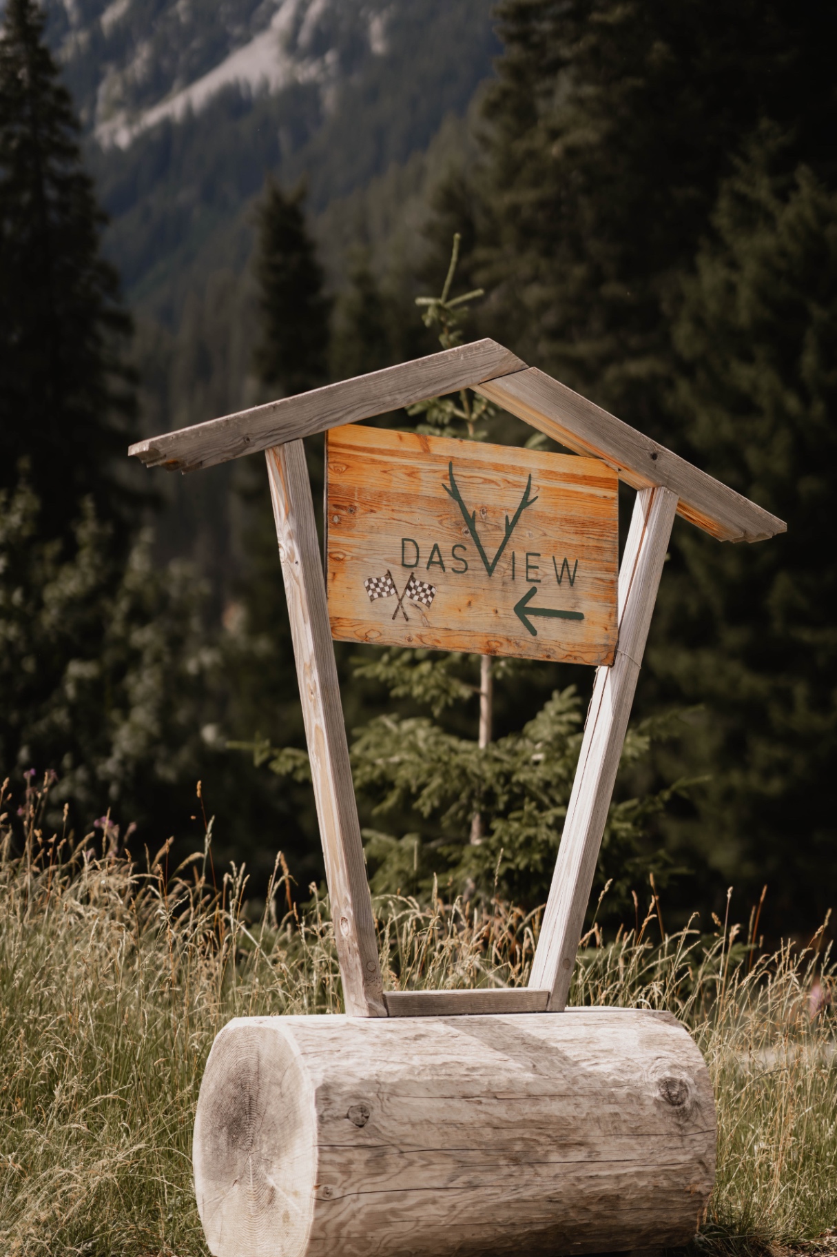 Holzschild weist den Weg zur Hochzeitslocation in den Alpen