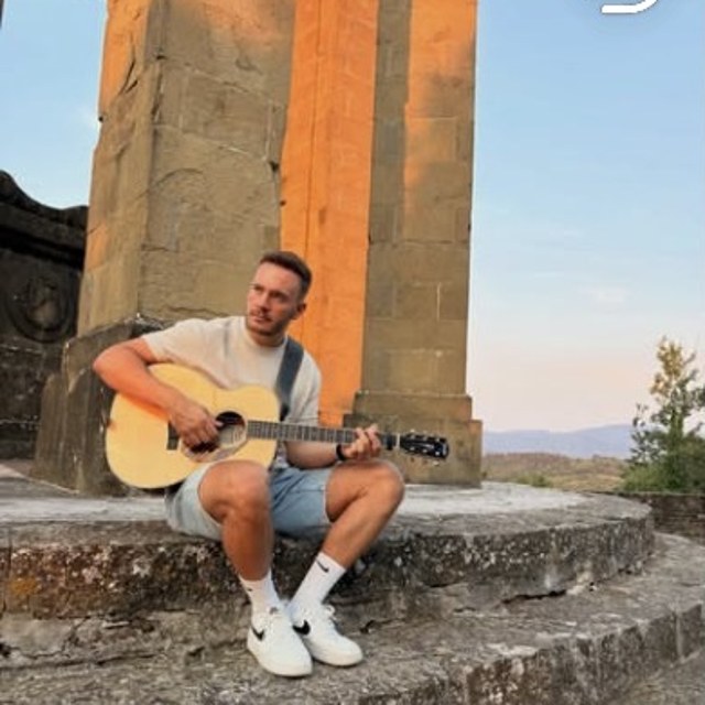 Dennis Ross spielt Gitarre auf einer alten Steintreppe